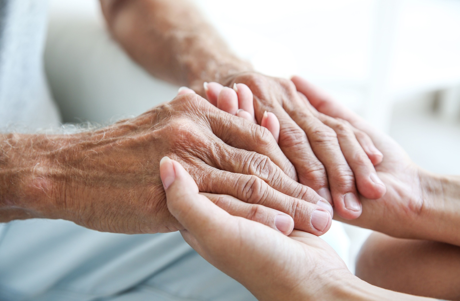 Close up of an older person's hands holding a younger person's hands