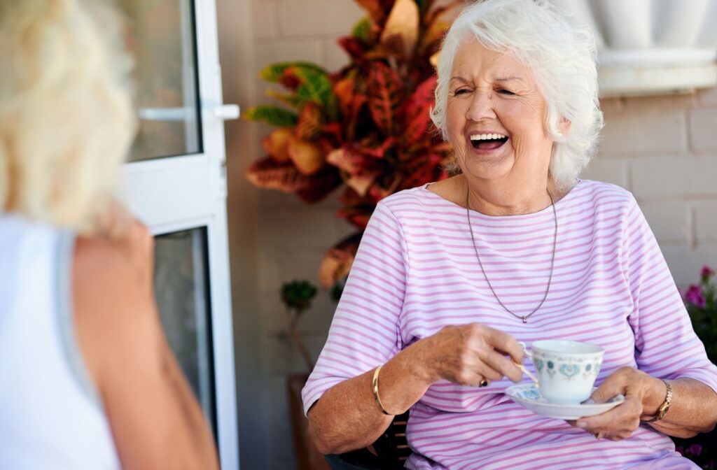 Two senior adult friends laughing and drinking tea together